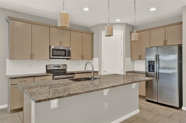 kitchen featuring a center island with sink, sink, appliances with stainless steel finishes, and decorative light fixtures