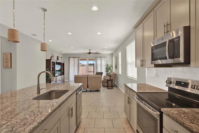 kitchen featuring stainless steel appliances, sink, decorative light fixtures, light stone counters, and ceiling fan