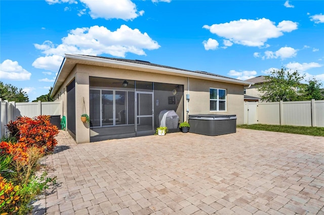 back of house with a sunroom, a hot tub, and a patio area