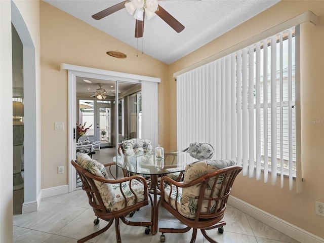 tiled dining room with ceiling fan, a textured ceiling, and vaulted ceiling