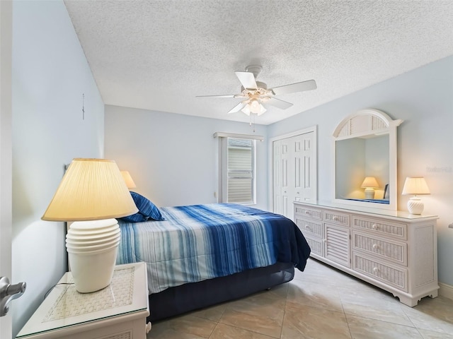 bedroom with light tile patterned floors, a textured ceiling, a closet, and ceiling fan