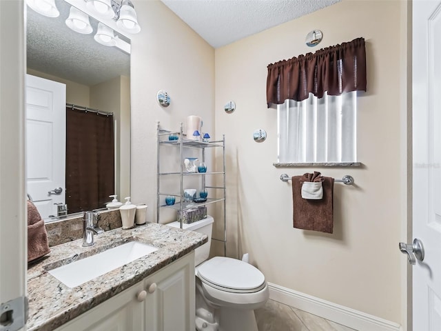 bathroom with vanity, toilet, a textured ceiling, and tile patterned flooring