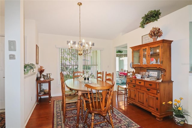 dining space with lofted ceiling, dark hardwood / wood-style flooring, and an inviting chandelier