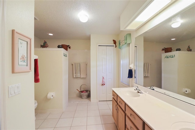 bathroom featuring vanity, toilet, a textured ceiling, and tile patterned flooring