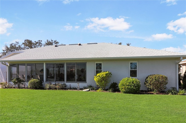 back of property with a yard and a sunroom