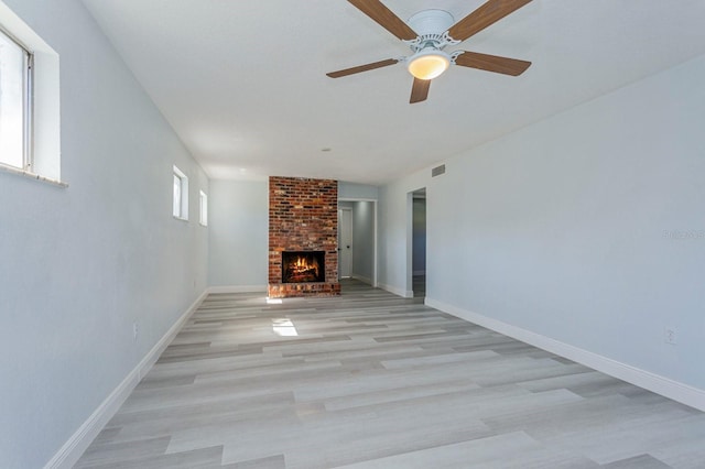 unfurnished living room featuring ceiling fan, light hardwood / wood-style flooring, and a fireplace