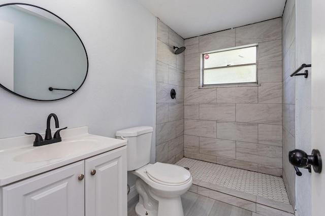 bathroom with vanity, toilet, and tiled shower