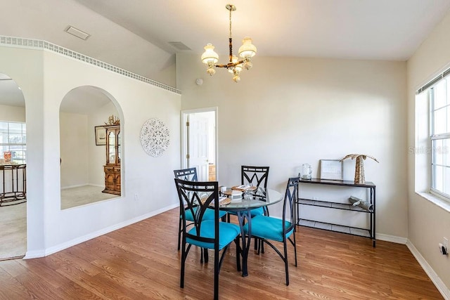 dining room featuring lofted ceiling, an inviting chandelier, and hardwood / wood-style floors