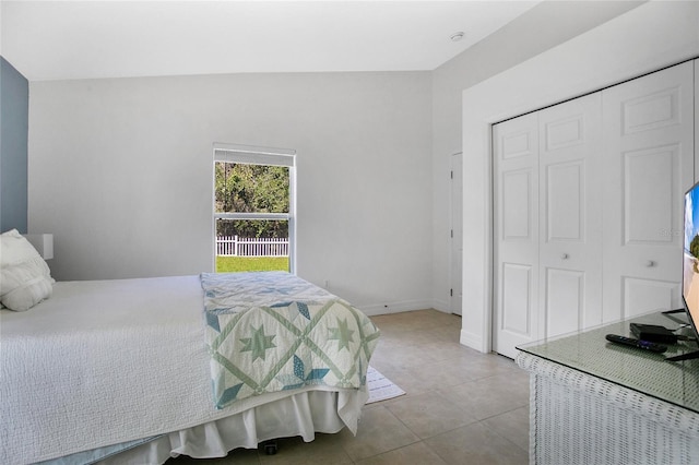 tiled bedroom featuring lofted ceiling and a closet