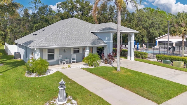 bungalow-style home featuring a fenced in pool, a front lawn, and central AC unit