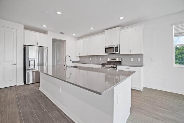 kitchen featuring sink, a kitchen island with sink, stainless steel appliances, and white cabinets