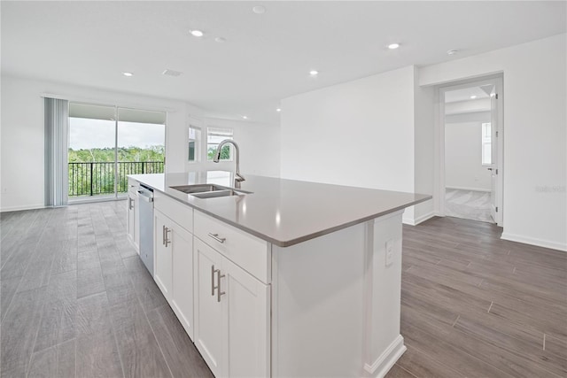 kitchen featuring white cabinets, a center island with sink, wood-type flooring, dishwasher, and sink