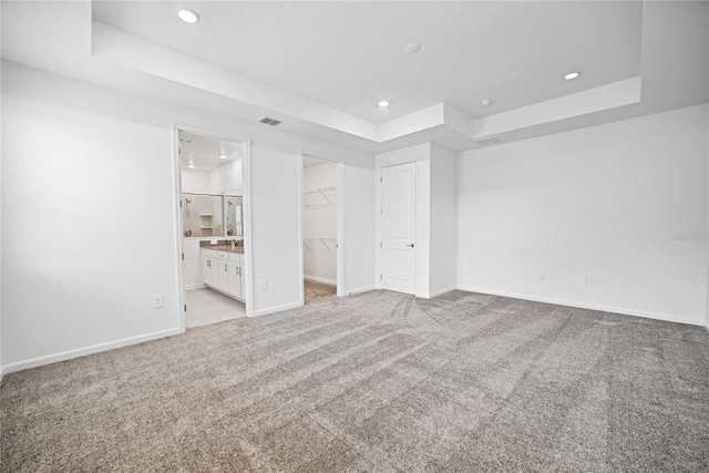 unfurnished room with light carpet and a tray ceiling