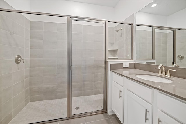 bathroom with a shower with door, vanity, and tile patterned flooring