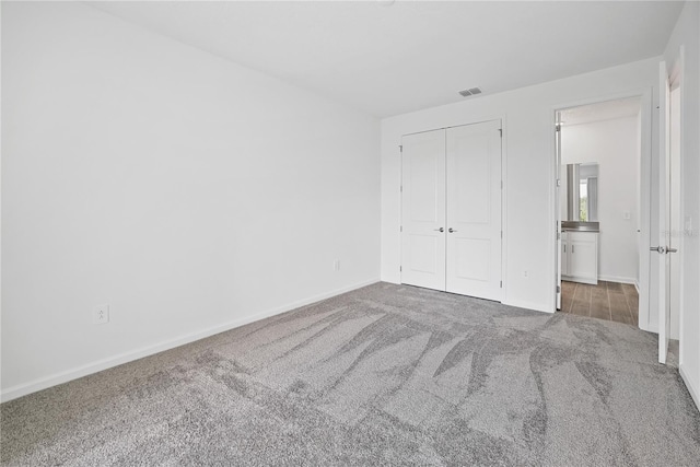 unfurnished bedroom featuring a closet and dark carpet