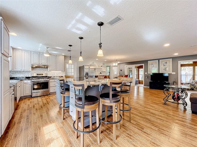 kitchen featuring light hardwood / wood-style flooring, dark stone counters, a breakfast bar, white cabinets, and appliances with stainless steel finishes