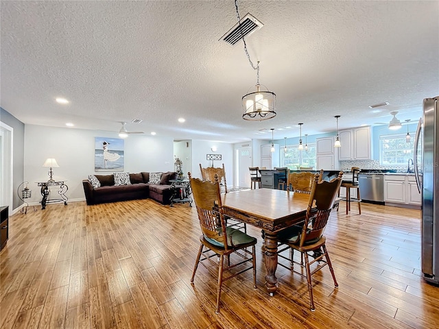 dining space featuring light hardwood / wood-style floors and a textured ceiling