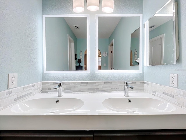 bathroom featuring vanity and backsplash