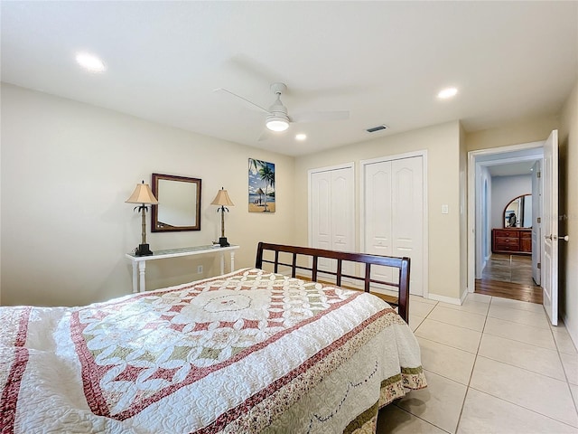 bedroom featuring multiple closets, light tile patterned floors, and ceiling fan