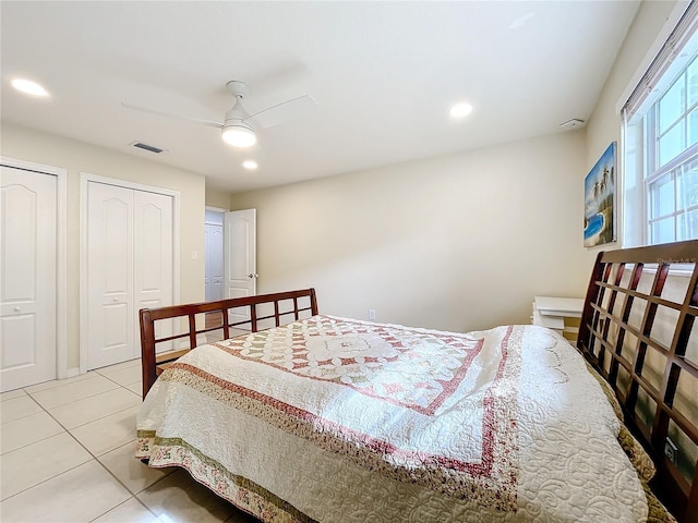 bedroom featuring two closets, light tile patterned floors, and ceiling fan