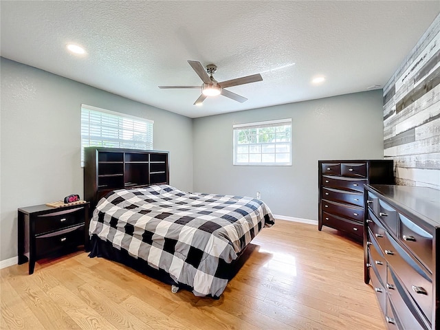 bedroom with light hardwood / wood-style floors, multiple windows, a textured ceiling, and ceiling fan