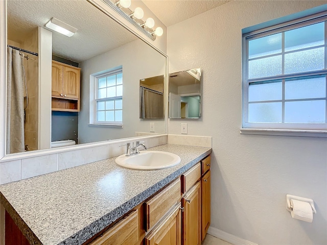 bathroom with toilet, a textured ceiling, and vanity