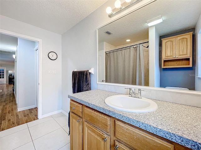 bathroom featuring vanity, a textured ceiling, toilet, and tile patterned flooring