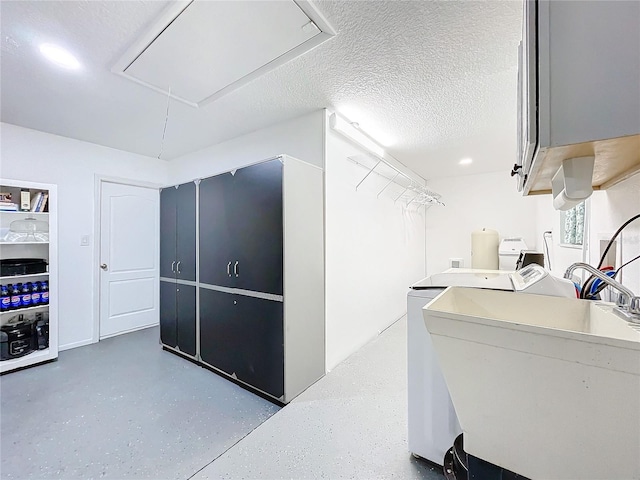 clothes washing area with cabinets, a textured ceiling, and washing machine and dryer