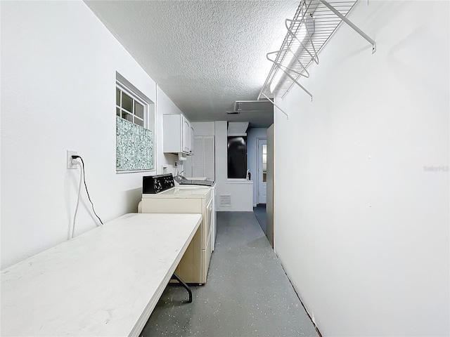 laundry area with washer and clothes dryer, a textured ceiling, and cabinets