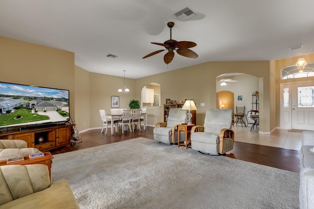 living room featuring wood-type flooring, ceiling fan with notable chandelier, and vaulted ceiling