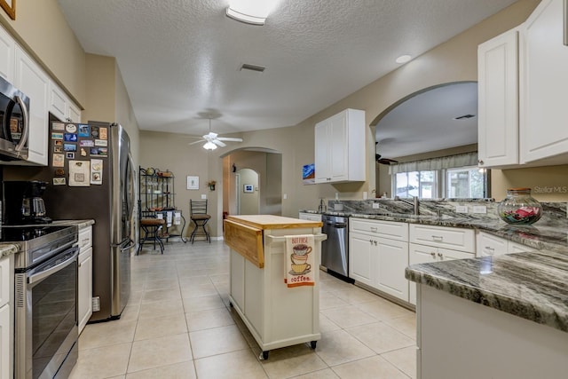 kitchen with white cabinetry, stainless steel appliances, and dark stone counters