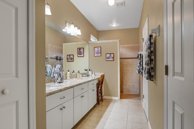 bathroom with vanity, a textured ceiling, tiled shower, and tile patterned flooring