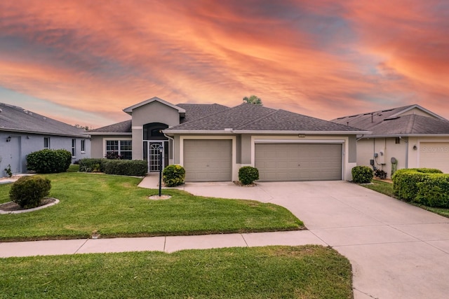 ranch-style house with a garage and a lawn