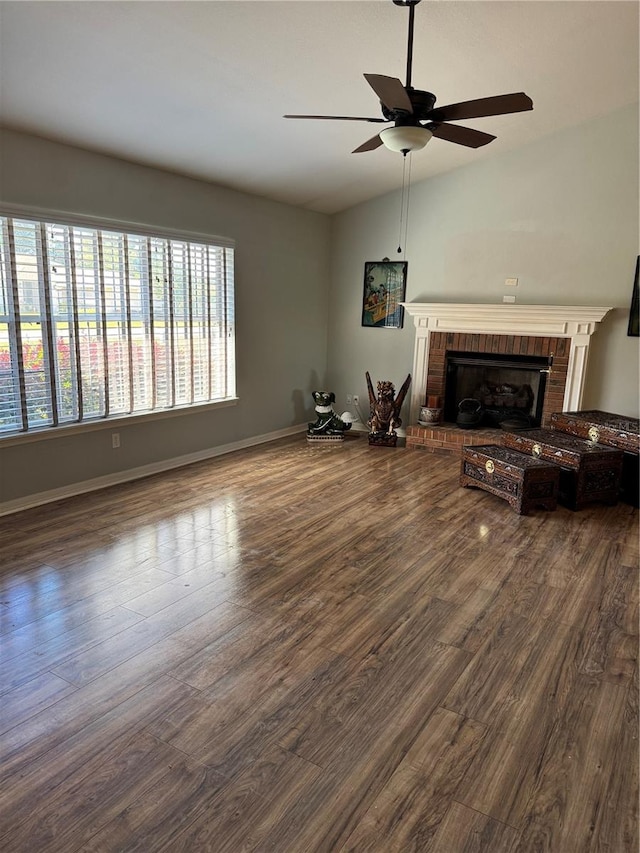 unfurnished living room featuring ceiling fan, vaulted ceiling, a brick fireplace, and dark hardwood / wood-style flooring