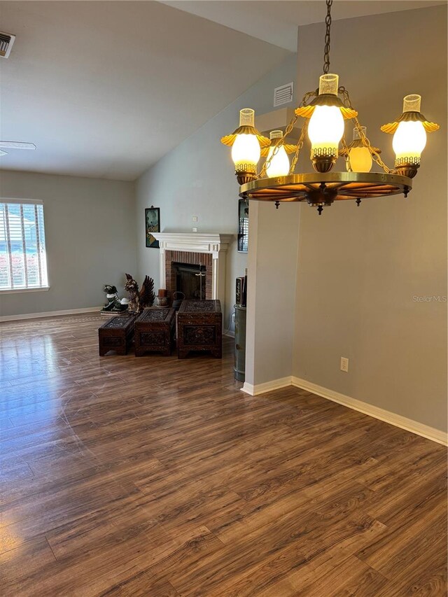 interior space with lofted ceiling, a brick fireplace, and dark hardwood / wood-style floors