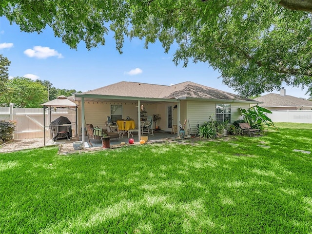 rear view of property featuring a patio, a gazebo, and a lawn