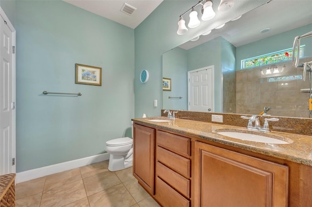 bathroom featuring vanity, toilet, a tile shower, and tile patterned flooring