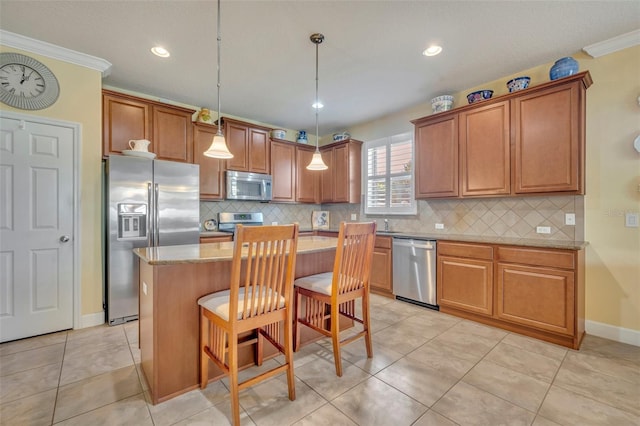 kitchen with a kitchen island, hanging light fixtures, stainless steel appliances, ornamental molding, and a breakfast bar