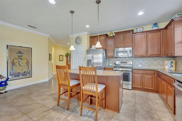 kitchen with a kitchen breakfast bar, light stone countertops, stainless steel appliances, pendant lighting, and a center island