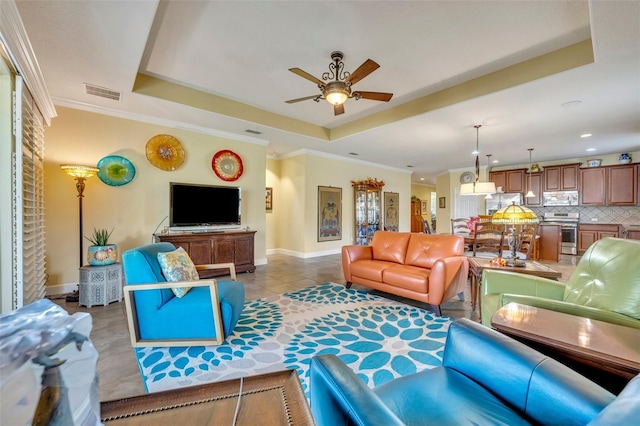 tiled living room featuring crown molding, a raised ceiling, and ceiling fan