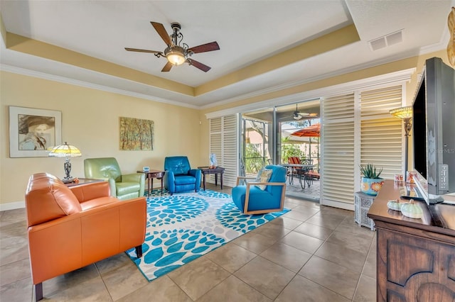 tiled living room featuring crown molding, a tray ceiling, and ceiling fan