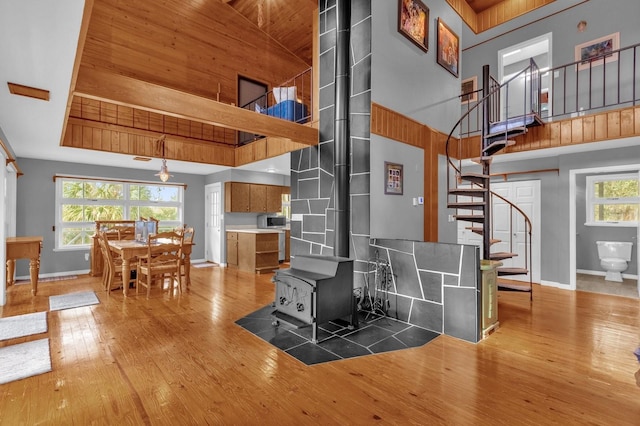 living room featuring a wood stove, a towering ceiling, plenty of natural light, and hardwood / wood-style flooring