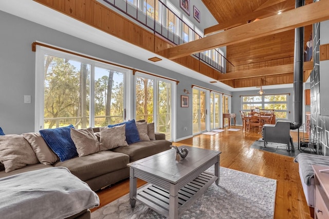 living room featuring high vaulted ceiling, beamed ceiling, wooden ceiling, and light hardwood / wood-style flooring