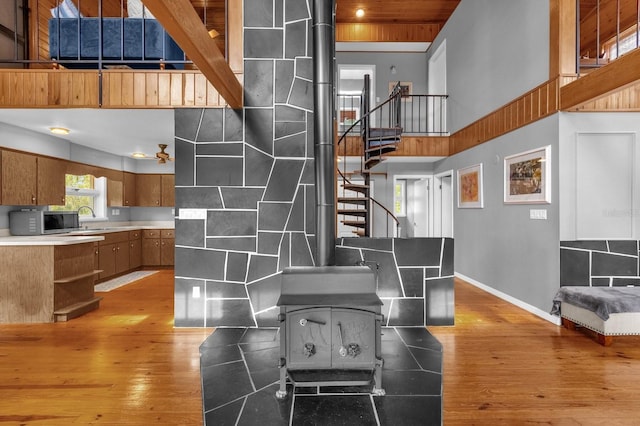 kitchen featuring a wood stove, hardwood / wood-style floors, sink, and a high ceiling