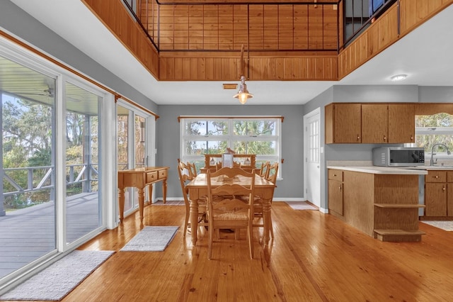 dining room featuring a towering ceiling, a wealth of natural light, light hardwood / wood-style flooring, and sink