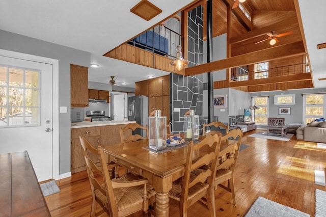 dining area featuring high vaulted ceiling, wood ceiling, beamed ceiling, ceiling fan, and light hardwood / wood-style flooring