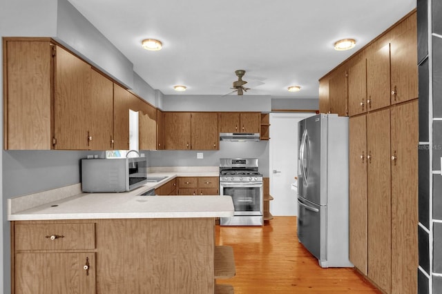 kitchen with light hardwood / wood-style floors, kitchen peninsula, ceiling fan, extractor fan, and appliances with stainless steel finishes