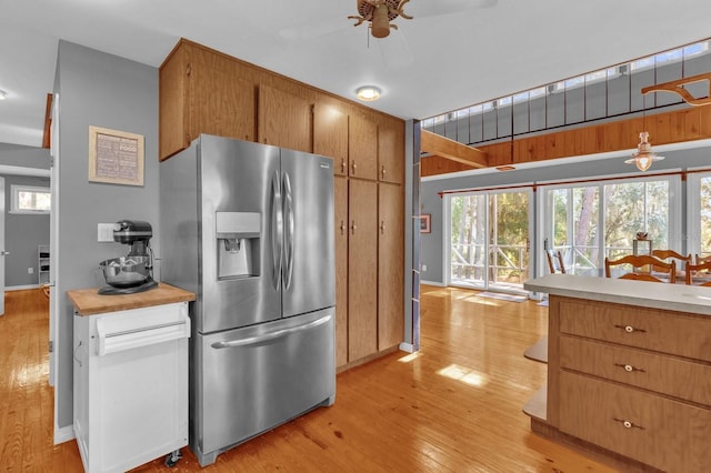 kitchen featuring ceiling fan, stainless steel fridge with ice dispenser, light wood-type flooring, and decorative light fixtures