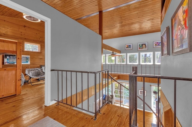 corridor featuring wooden ceiling, wood walls, light hardwood / wood-style flooring, and lofted ceiling