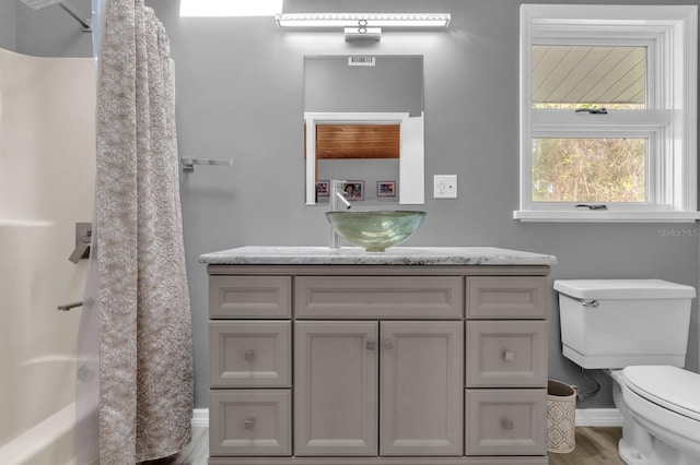 full bathroom with hardwood / wood-style floors, vanity, shower / bath combo with shower curtain, and toilet